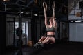 Young active strong sweaty athlete muscular fit girl with big muscles doing cross workout training on the gymnastic rings for hole