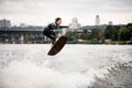 Young active woman rides wakeboard and jumps holds her hands on rope Royalty Free Stock Photo