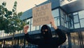 young activist in balaclava holding placard