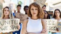 Young activist woman with arms crossed gesture standing with a group of protesters holding banner protesting at the city Royalty Free Stock Photo
