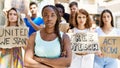 Young activist woman with arms crossed gesture standing with a group of protesters holding banner protesting at the city Royalty Free Stock Photo