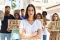Young activist woman with arms crossed gesture standing with a group of protesters holding banner protesting at the city Royalty Free Stock Photo