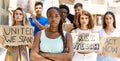 Young activist woman with arms crossed gesture standing with a group of protesters holding banner protesting at the city Royalty Free Stock Photo