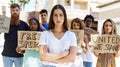 Young activist woman with arms crossed gesture standing with a group of protesters holding banner protesting at the city Royalty Free Stock Photo