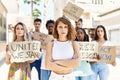 Young activist woman with arms crossed gesture standing with a group of protesters holding banner protesting at the city Royalty Free Stock Photo