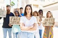 Young activist woman with arms crossed gesture standing with a group of protesters holding banner protesting at the city Royalty Free Stock Photo