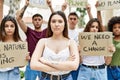 Young activist woman with arms crossed gesture standing with a group of protesters holding protest banner at the city Royalty Free Stock Photo