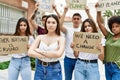 Young activist woman with arms crossed gesture standing with a group of protesters holding protest banner at the city Royalty Free Stock Photo