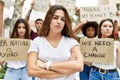 Young activist woman with arms crossed gesture standing with a group of protesters holding protest banner at the city Royalty Free Stock Photo