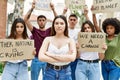 Young activist woman with arms crossed gesture standing with a group of protesters holding protest banner at the city Royalty Free Stock Photo