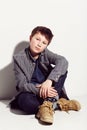 Relaxed and easy style. Young adolescent boy sitting against a white background. Royalty Free Stock Photo