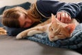 An Young Adolescent girl lying on a couch finds comfort by snuggling close to and petting her cat Royalty Free Stock Photo