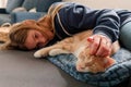 An Young Adolescent girl lying on a couch finds comfort by snuggling close to and petting her cat Royalty Free Stock Photo