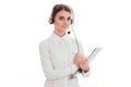 Young adorable business woman in uniform with headphones and microphone looking at the camera and make notes isolated on Royalty Free Stock Photo