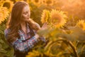 Young, adorable, energetic, female farmer examining sunflowers in the middle of a beautiful sunflower field, during a scenic Royalty Free Stock Photo