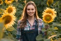 Young, adorable, energetic, female farmer posing for the camera in the middle of a sunflower field during sunrise Royalty Free Stock Photo