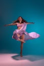 Young adorable flexible contemp dancer in lilac dress dancing on gradient blue white background in neon.