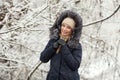 Young adorable woman wearing blue hooded coat enjoying strolling in winter forest outdoors. Nature cold season freshness concept. Royalty Free Stock Photo