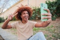 Young adult african american male taking a selfie portrait with a cellphone smiling with a toothy smile. Happy teenage Royalty Free Stock Photo