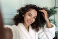 Young adult afro american woman in bathrobe making self portrait