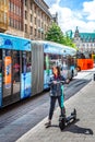 Young adult Asian female on electric scooter in front of The Town Hall in Hamburg, Germany