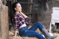 Young adult Asian woman fashion in natural environment. Beautiful cowgirl in the stable. Cheerful cute model in western style. Cow Royalty Free Stock Photo