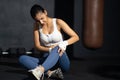 Young adult Asian women feeling painful from knee muscle injury after workout with weight lifting, cross training at fitness gym.