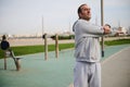 Young adult athletic man exercising outdoor, warming up his body before bodyweight workout on the urban sportsground