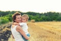 Young adult attractive beautiful mom holding on hand and hugging little son enjoy walking by golden wheat harvested Royalty Free Stock Photo