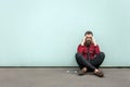 Young adult bearded businessman sits on the ground.