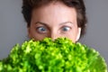 Young adult beautiful caucasian happy smiling woman portrait looking dedesire green fresh lettuce salad crop in front face. Royalty Free Stock Photo