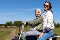 Young adult beautiful mother and daughter enjoy having fun riding electric scooter bike or rural countryside dirt road Royalty Free Stock Photo