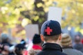 A young adult in a black cap with a red cross