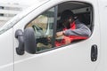 Young adult black delivery man wearing work uniform red pullover and black cap sitting in driver seat of white van Royalty Free Stock Photo