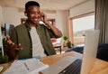 Young adult black male adjusting earphones while talking in online meeting. Sitting at kitchen counter using laptop.