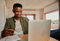Young adult black male excited to make online purchase on laptop in modern apartment.