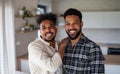 Young adult brothers in kitchen indoors at home, looking at camera. Royalty Free Stock Photo