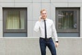 Young adult businessman calling his boss, looking at camera and smiling. Royalty Free Stock Photo