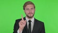 Young Businessman in Denial on Green Background