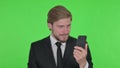 Young Businessman Loss on Smartphone on Green Background