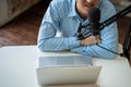 Young adult businessman podcasting and recording talk show at home studio with computer laptop on table. The desk is