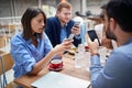 Young adult businesspeople at lunch in a restaurant checking their cell phones for any good news after coronavirus. covid 19,