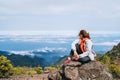 Young adult caucasian female dressed sporty clothes resting on the rock and enjoying clouds view from Pico Ruivo mount 1861m -