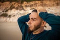 Young adult Caucasian man and hippie look on the beach holding his head with both hands. Attitude of surprise Royalty Free Stock Photo