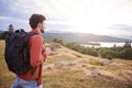 A young adult Caucasian man walking alone on a hill, admiring the view, side view