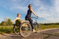 Young adult caucasian mom enjoy having leisure fun riding bicycle with cute adorable blond daughter holding wild field