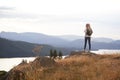 A young adult Caucasian woman standing alone on the rock after hiking, admiring lake view, back view