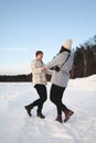 Young adult couple cheerfully flounders in snowy forest. Comic fight. Happy young couple hugs in winter Royalty Free Stock Photo