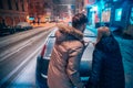 Young adult couple draws a heart on snow covered car