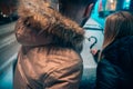 Young adult couple draws a heart on snow covered car